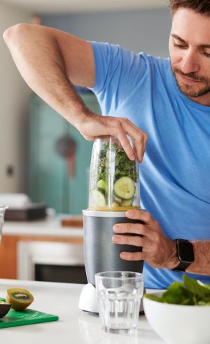 Man Making Healthy Juice Drink With Fresh Ingredients In Electric Juicer After Exercise